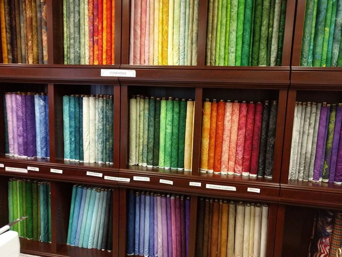 Walls of colorful quilting cotton bolts in a small shop