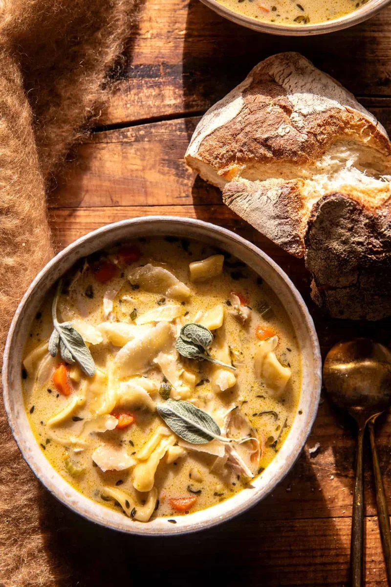 Creamy chicken noodle soup with bread on a wooden table