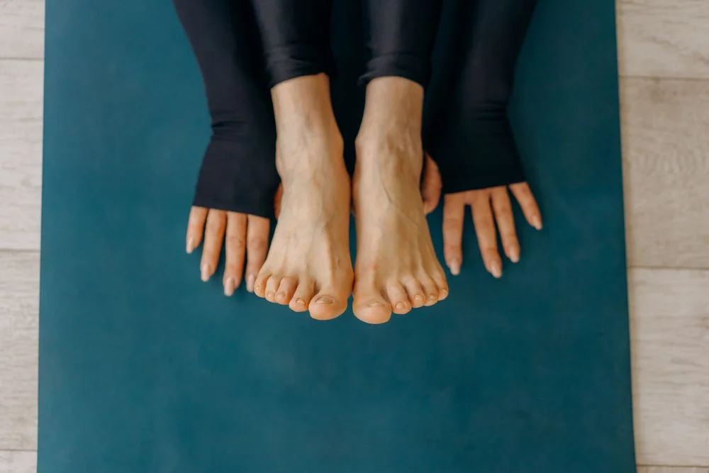 Seated person with bare feet flat on a teal exercise mat