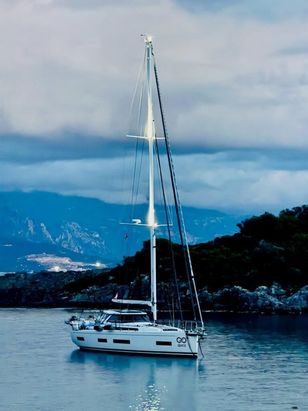 Sailboat anchored in calm water near a rocky coastline